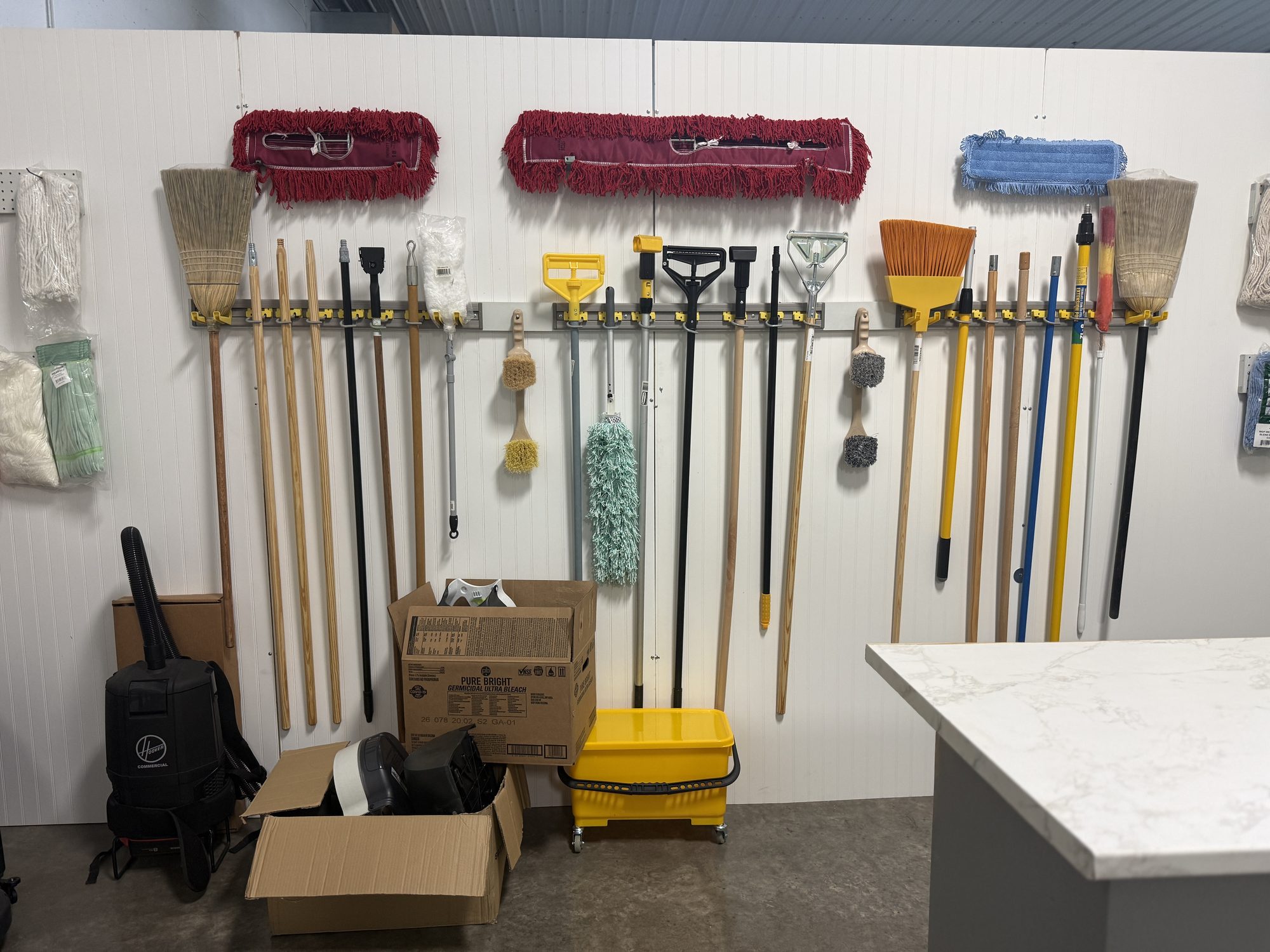 Wall of mops and brooms ready for pickup